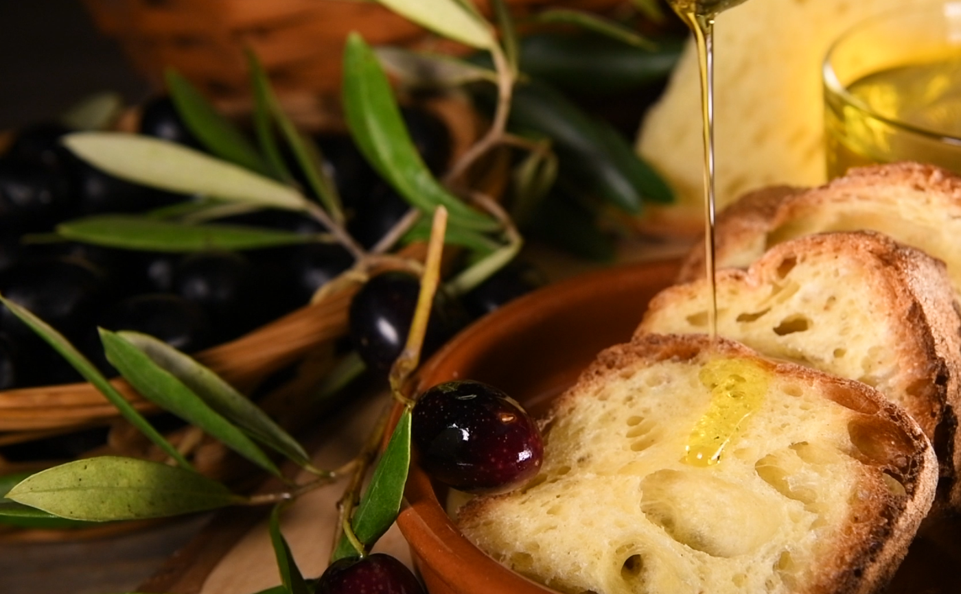 olio, ramo di olive e fette di pane su cui viene versato l'olio
